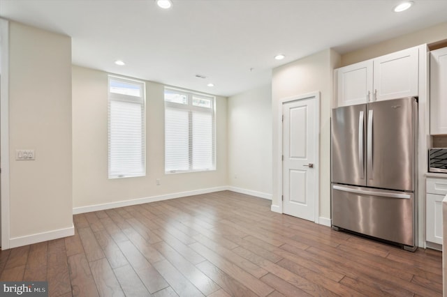 kitchen with stainless steel fridge, light hardwood / wood-style floors, and white cabinetry