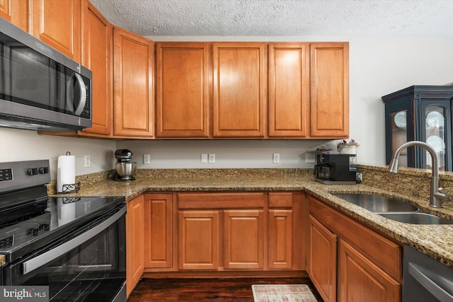 6330 Kleineidam Way, Spotsylvania, VA 22551 - kitchen featuring stone counters, a sink, stainless steel appliances, brown cabinetry, and dark wood-style floors