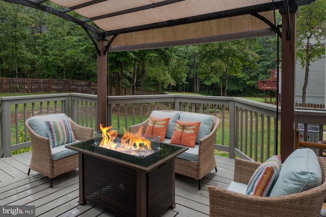 wooden deck featuring an outdoor living space with a fire pit