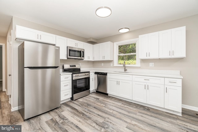 kitchen with white cabinetry, sink, light hardwood / wood-style floors, and appliances with stainless steel finishes