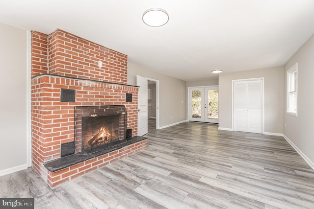 unfurnished living room featuring a fireplace, french doors, and light hardwood / wood-style floors