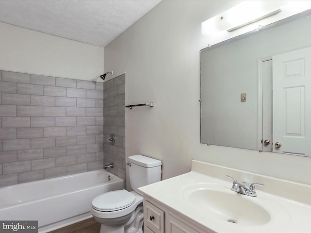 full bathroom featuring a textured ceiling, vanity, toilet, and tiled shower / bath