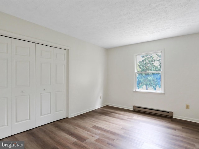 unfurnished bedroom with a baseboard radiator, a closet, hardwood / wood-style floors, and a textured ceiling