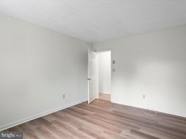 spare room with a textured ceiling and light hardwood / wood-style floors