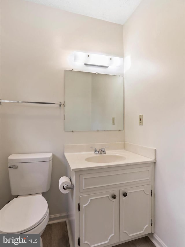 bathroom featuring wood-type flooring, vanity, and toilet