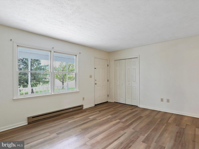 unfurnished bedroom with light wood-type flooring, a textured ceiling, and a baseboard radiator