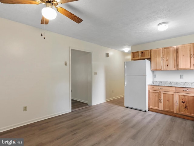 kitchen featuring ceiling fan, white refrigerator, a textured ceiling, and hardwood / wood-style flooring