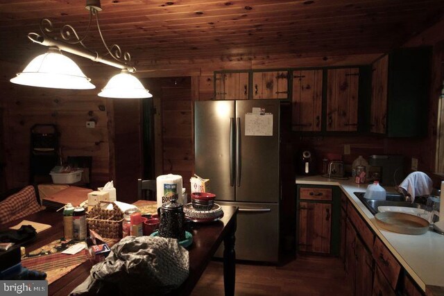 kitchen featuring dark hardwood / wood-style floors, stainless steel fridge, wooden ceiling, hanging light fixtures, and wooden walls