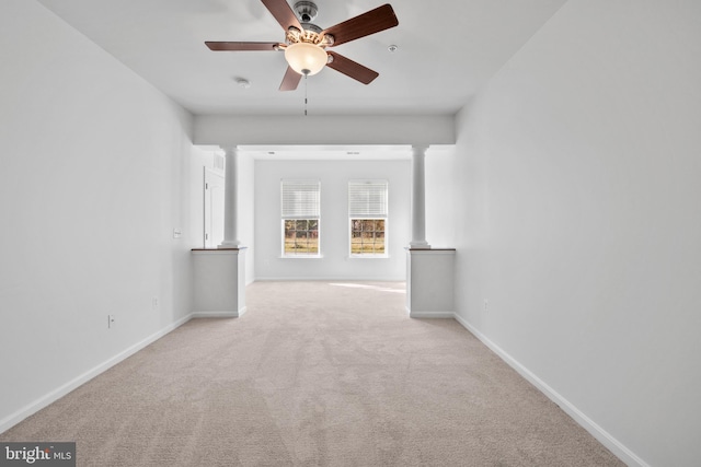 carpeted spare room featuring ornate columns and ceiling fan