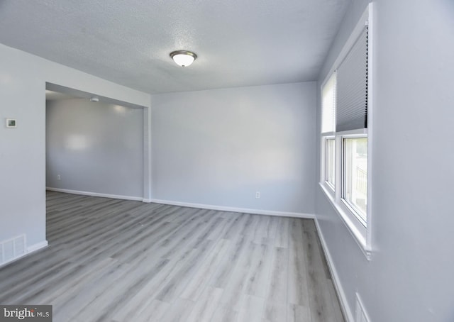 unfurnished room with a textured ceiling and light hardwood / wood-style flooring