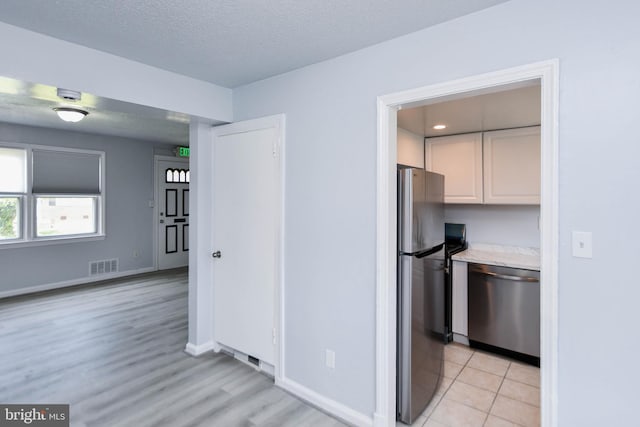 kitchen with appliances with stainless steel finishes, light hardwood / wood-style floors, and a textured ceiling