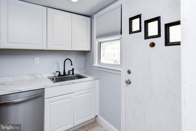 kitchen featuring dishwasher, sink, light tile patterned floors, and white cabinetry