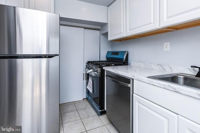 kitchen with white cabinetry, light stone counters, stainless steel appliances, and light tile patterned flooring