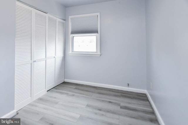 unfurnished bedroom with light wood-type flooring and a closet