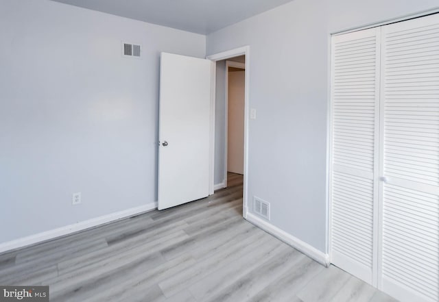 unfurnished bedroom with light wood-type flooring and a closet