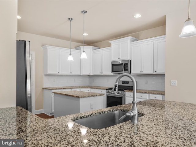 kitchen with white cabinets, decorative light fixtures, light stone countertops, stainless steel appliances, and dark wood-type flooring