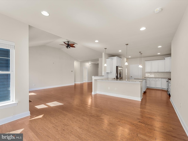 unfurnished living room featuring ceiling fan, sink, vaulted ceiling, and hardwood / wood-style flooring