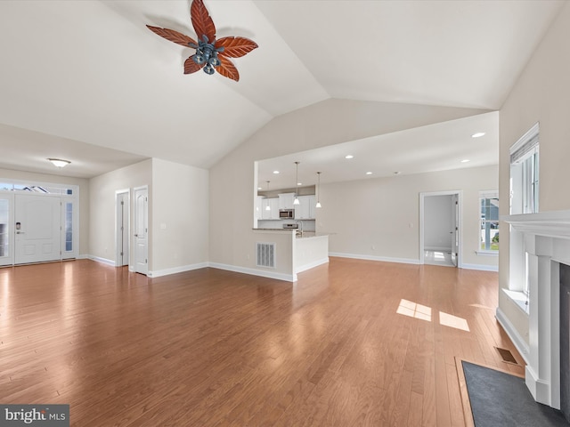 unfurnished living room featuring lofted ceiling, hardwood / wood-style floors, and ceiling fan