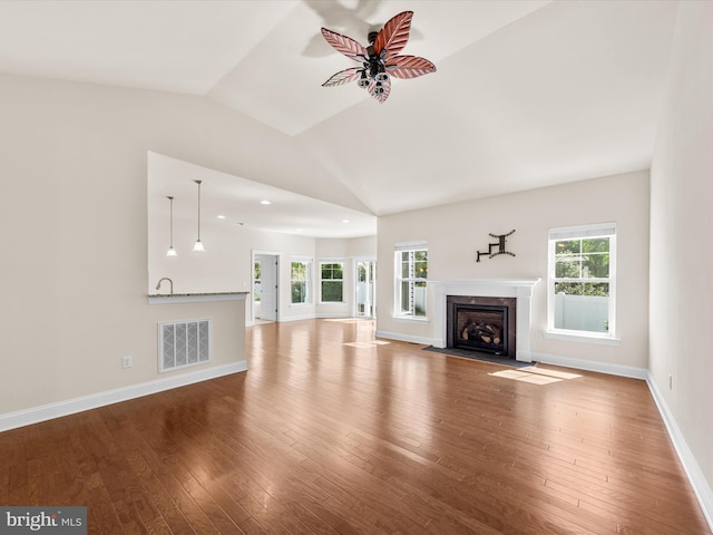 unfurnished living room featuring ceiling fan, vaulted ceiling, hardwood / wood-style flooring, and a fireplace