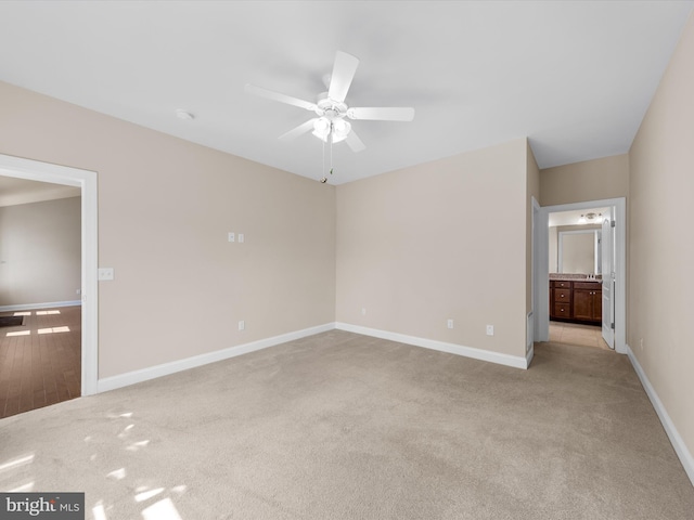 unfurnished bedroom featuring light colored carpet, ensuite bath, and ceiling fan