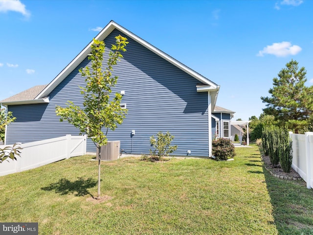 view of side of property featuring central AC and a lawn