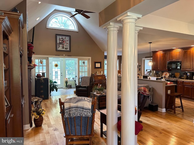 living room with decorative columns, high vaulted ceiling, light hardwood / wood-style flooring, and ceiling fan