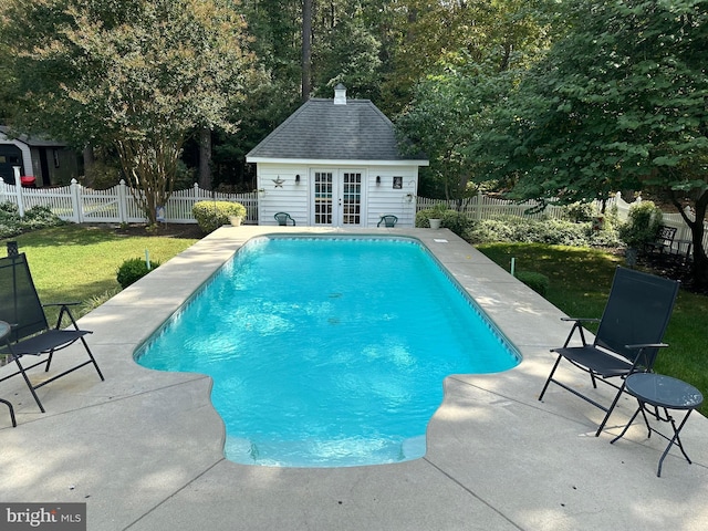 view of swimming pool featuring a yard, an outbuilding, and a patio area