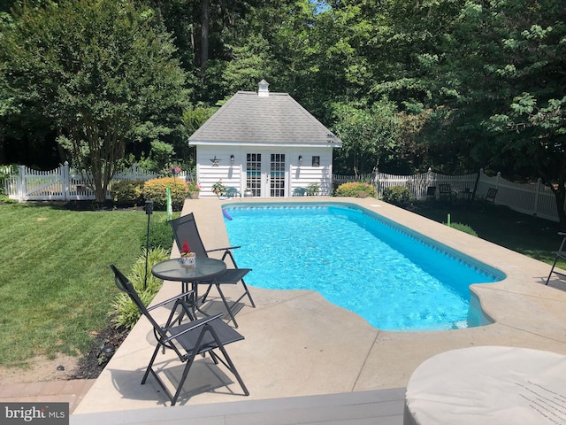 view of pool featuring a lawn, a patio area, and an outbuilding