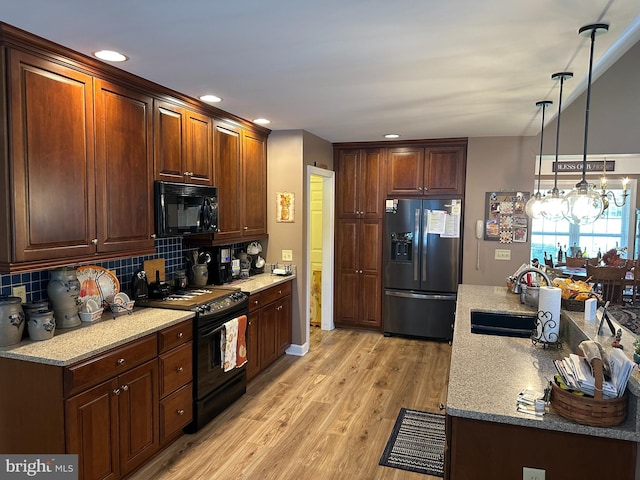 kitchen with light stone countertops, black appliances, backsplash, sink, and light wood-type flooring