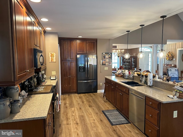 kitchen with hanging light fixtures, vaulted ceiling, light wood-type flooring, stainless steel appliances, and sink