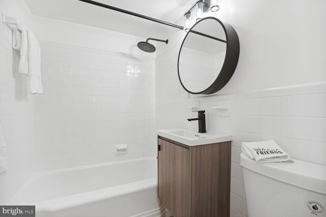 full bathroom with vanity, tile walls, tiled shower / bath combo, and toilet