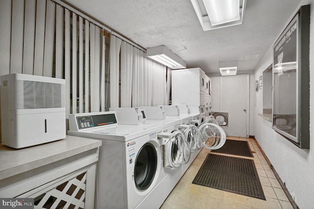 laundry room featuring stacked washer / drying machine, light tile patterned floors, a textured ceiling, and washing machine and clothes dryer