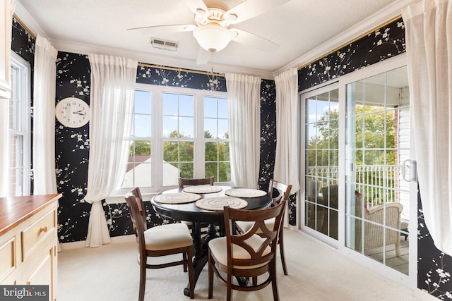 dining space with crown molding, ceiling fan, light colored carpet, and a wealth of natural light