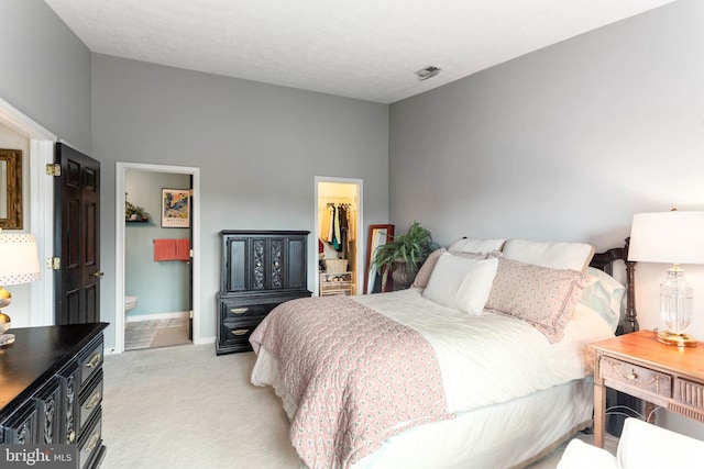 carpeted bedroom with a closet, ensuite bathroom, high vaulted ceiling, and a walk in closet