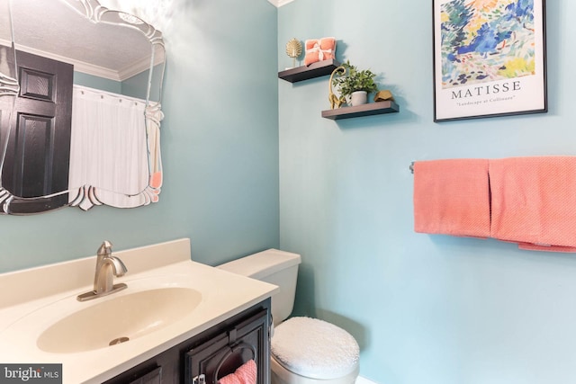 bathroom with a textured ceiling, crown molding, vanity, and toilet