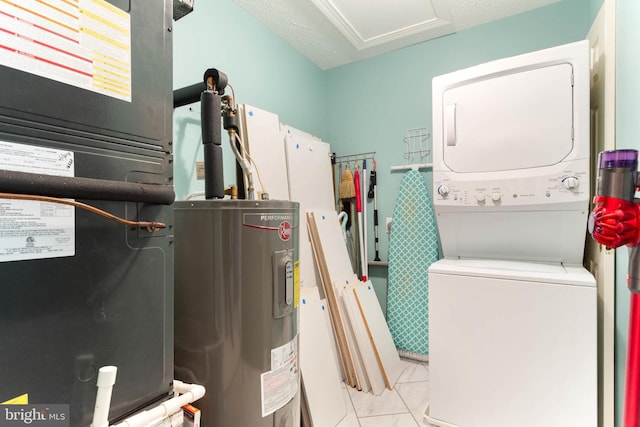 clothes washing area featuring water heater, stacked washer and dryer, and a textured ceiling