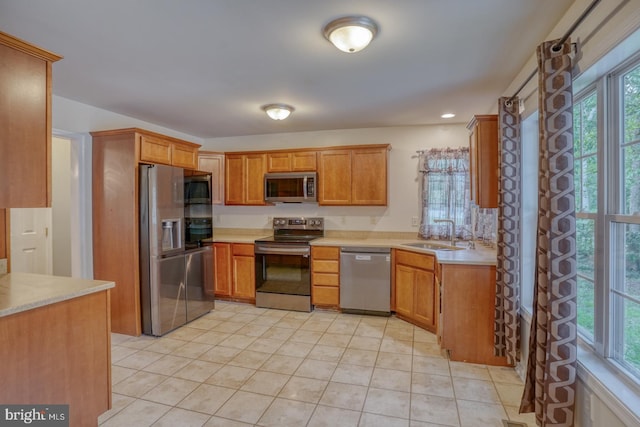 kitchen featuring light tile patterned flooring, stainless steel appliances, plenty of natural light, and sink