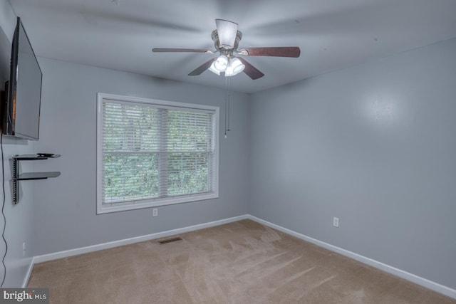 carpeted spare room featuring ceiling fan