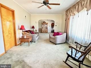 carpeted living room featuring ceiling fan and ornamental molding