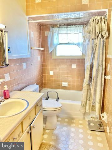 full bathroom featuring tile walls, vanity, toilet, and shower / bathtub combination with curtain