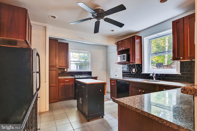 kitchen featuring sink, a kitchen island, a healthy amount of sunlight, and black appliances