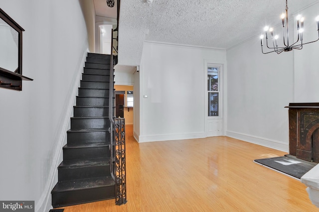 staircase featuring a textured ceiling, wood-type flooring, and a chandelier