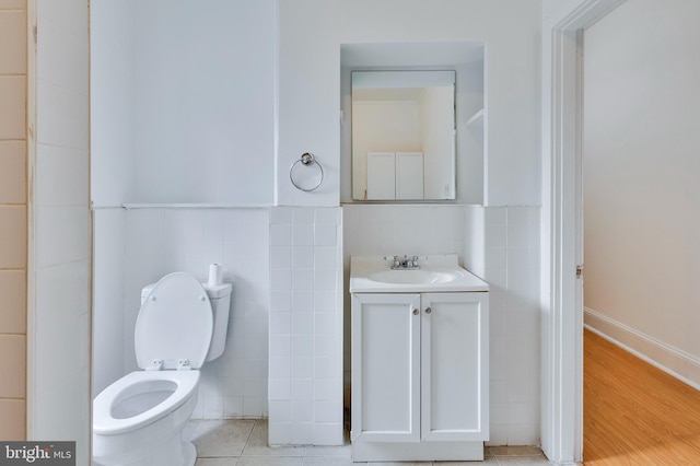 bathroom with toilet, hardwood / wood-style flooring, vanity, and tile walls