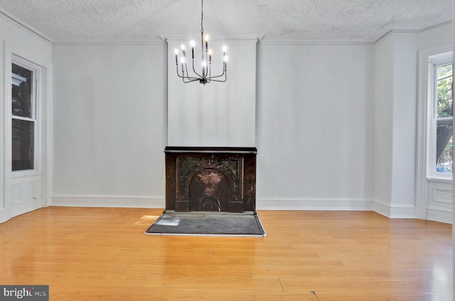 unfurnished living room with ornamental molding, hardwood / wood-style floors, a notable chandelier, and a textured ceiling