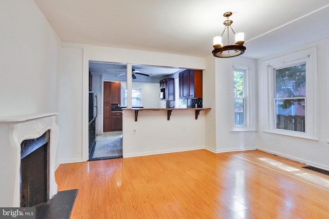 unfurnished living room featuring light hardwood / wood-style flooring and ceiling fan with notable chandelier