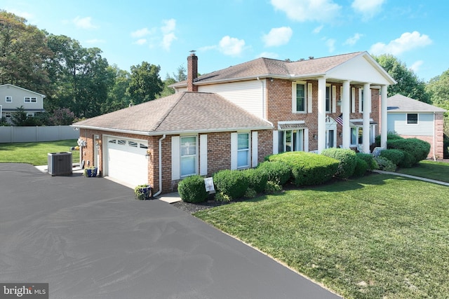 greek revival house featuring a garage, a front lawn, and cooling unit