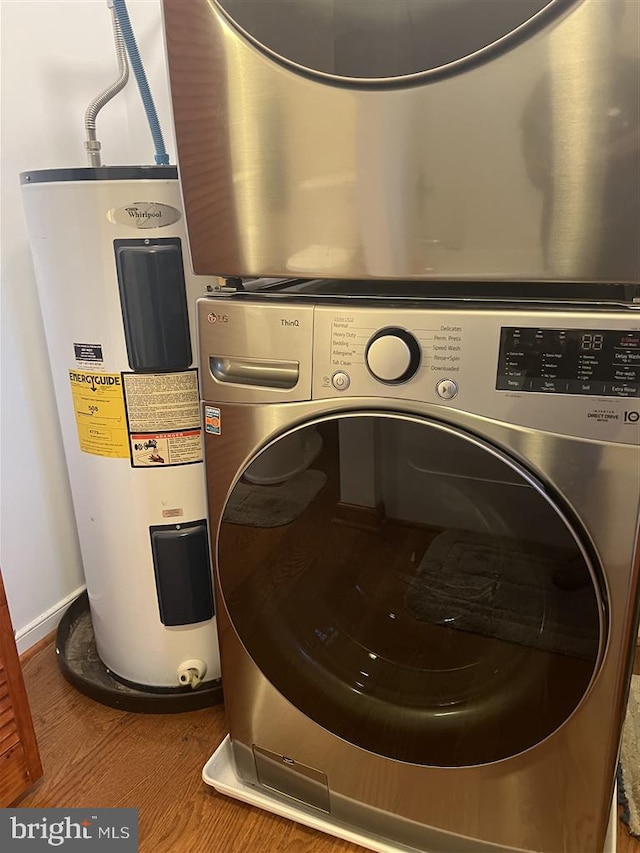 washroom with stacked washer and dryer, water heater, and hardwood / wood-style floors