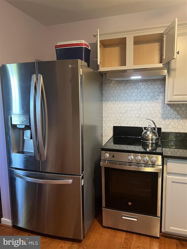 kitchen featuring appliances with stainless steel finishes, decorative backsplash, white cabinetry, light hardwood / wood-style floors, and extractor fan