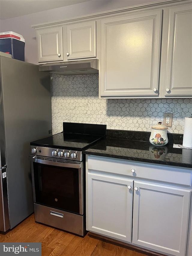 kitchen featuring dark hardwood / wood-style floors, white cabinets, stainless steel appliances, and tasteful backsplash