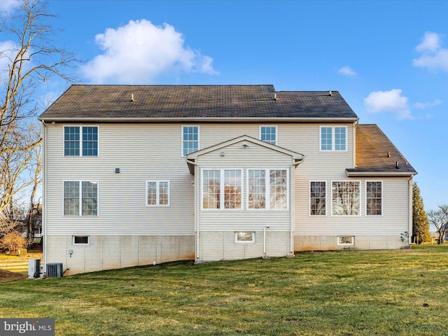 rear view of house with central AC unit and a lawn